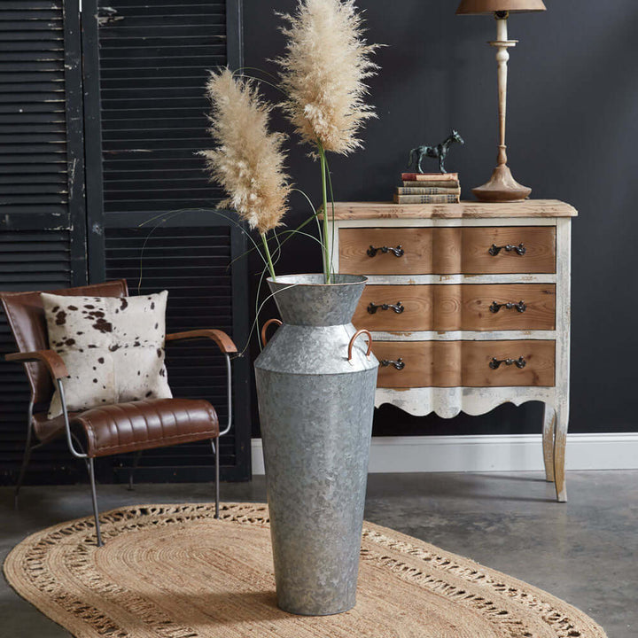 Rustic galvanized metal floor vase with handles and pampas grass, adding farmhouse charm to a stylish interior setting.