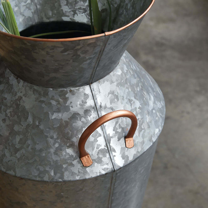 Rustic galvanized metal floor vase with copper handles and greenery, perfect for vintage home decor.