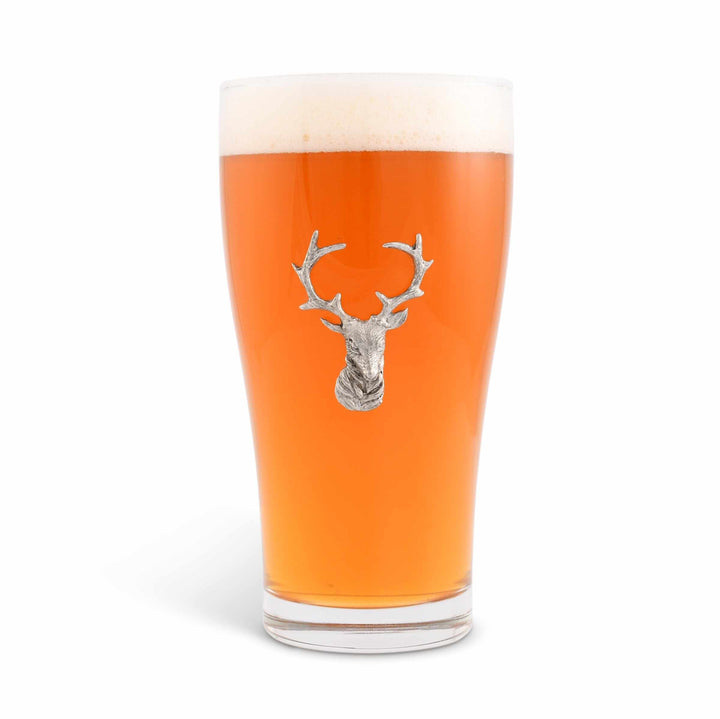 Pint glass with a deer head emblem filled with beer on a white background