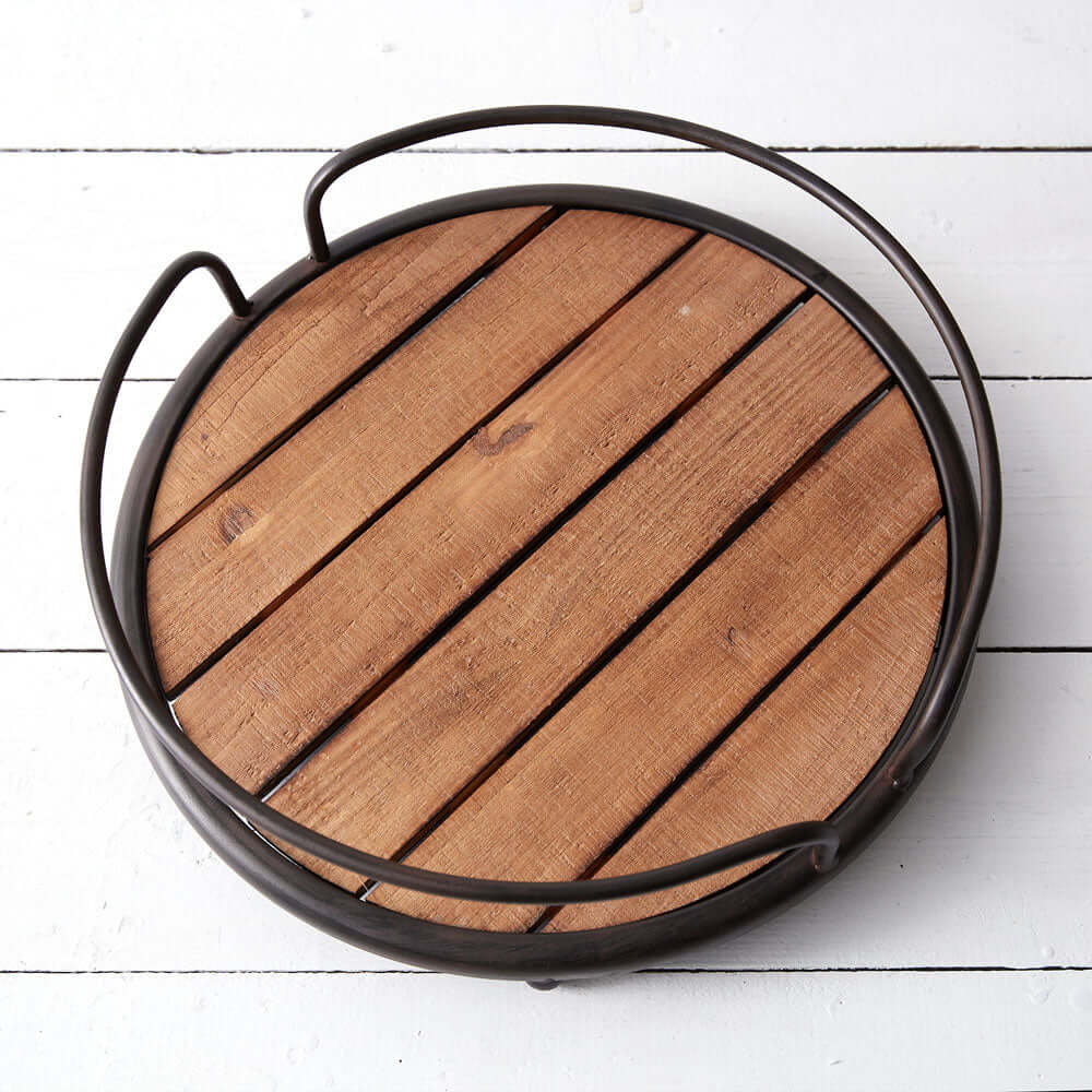 Rustic round wood tray with black metal handles, showcasing natural wood slats and vintage charm on a white surface.