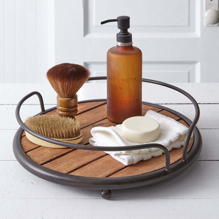 Rustic round wood tray with metal handles, featuring grooming products for a stylish bathroom setup.
