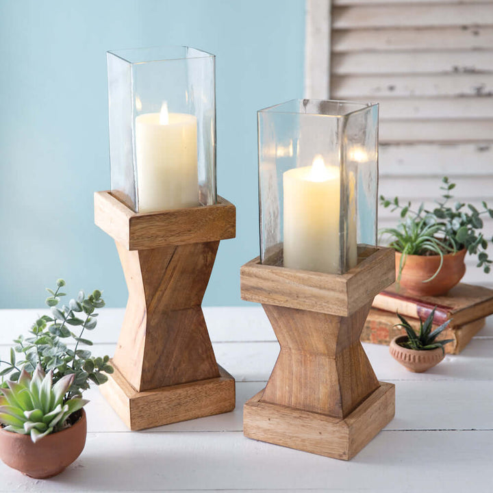 Rustic wood candle holders with glass chimneys, creating warm, nostalgic decor on a bright table setting.