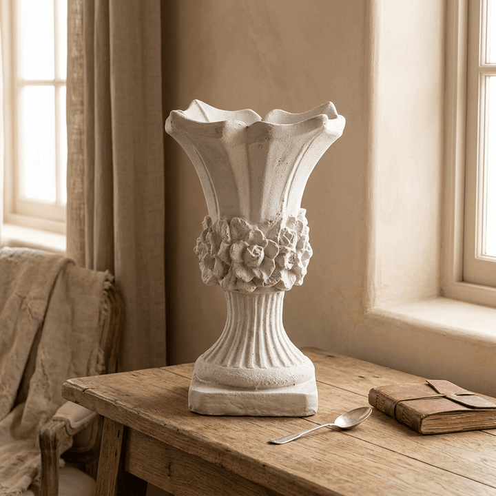 Pale distressed scalloped floral urn planter on an oak console, showing its raised flower band and fluted pedestal.