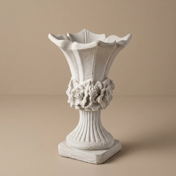 Studio view of the scalloped floral urn planter with an empty flared bowl, sculpted flowers, fluted stem, and square base.