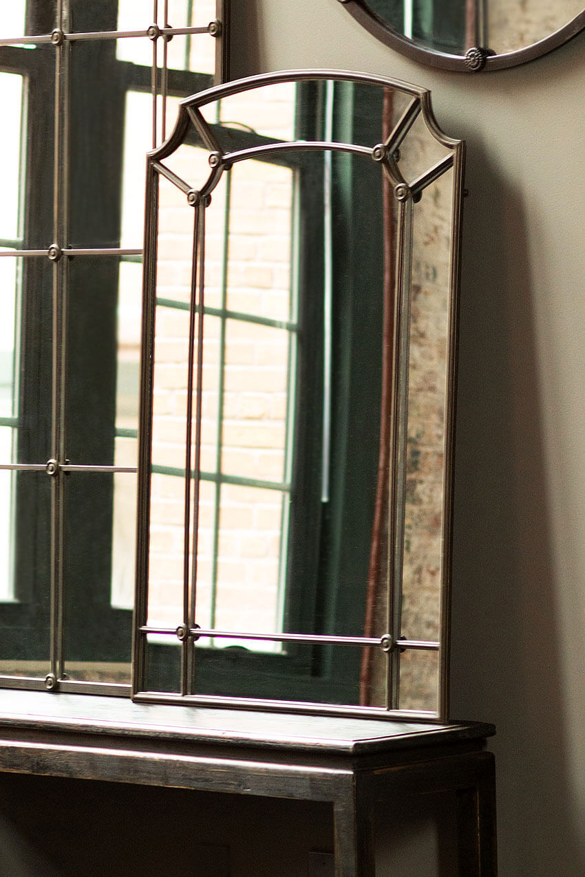 Structured Arched Wall Mirror in Iron with elegant design and dark bronze finish, enhancing home decor near window.