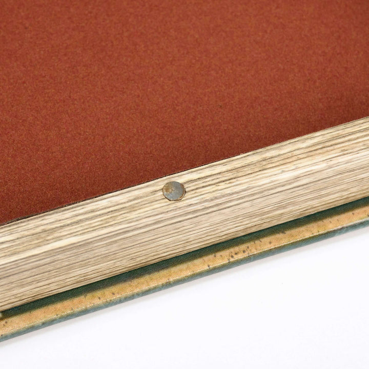 Close-up of a wooden frame corner with a metal screw on a red background