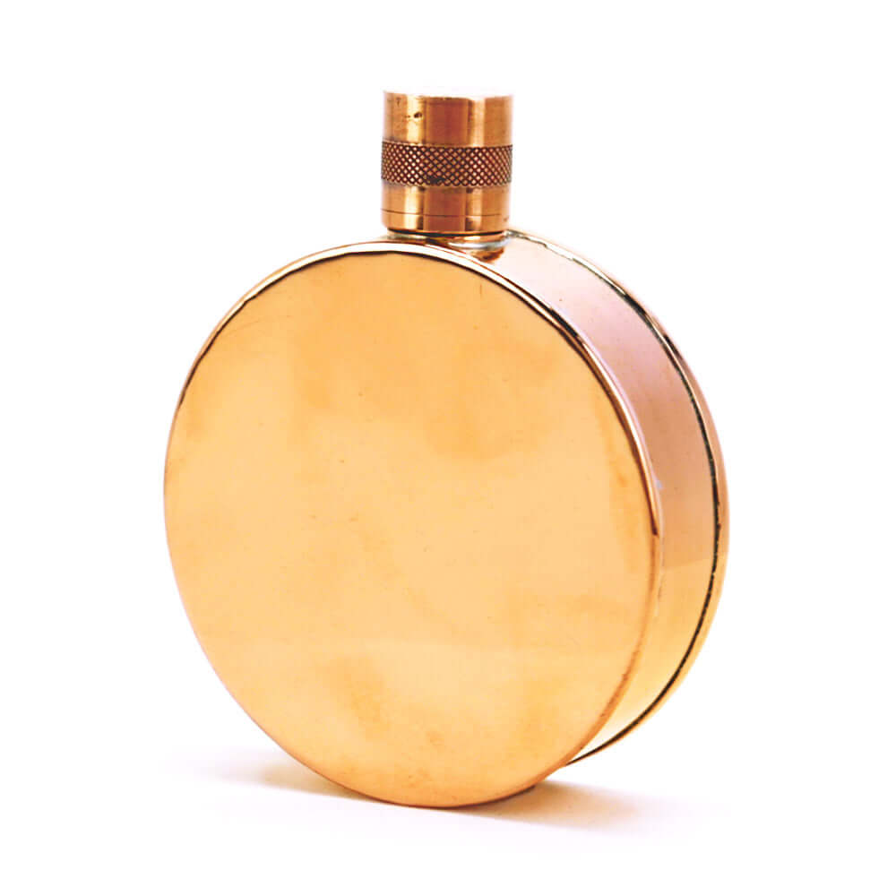 Round copper flask with a gold cap on a white background