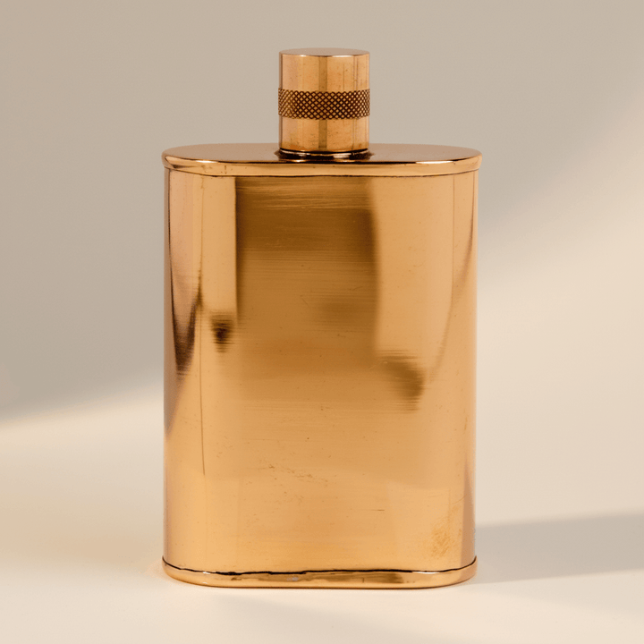 Copper flask with cap on a beige background
