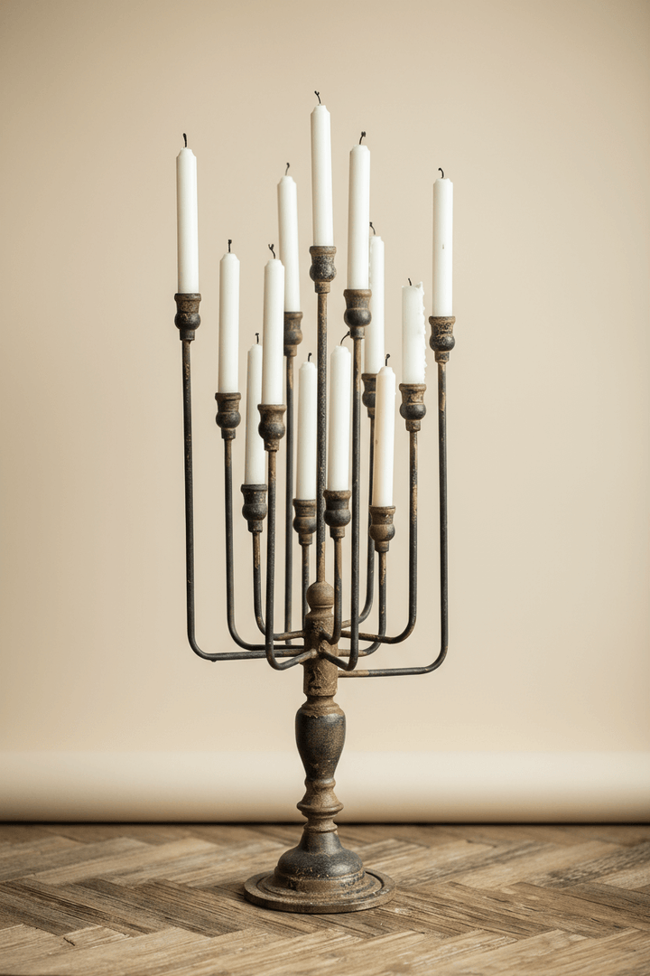 Decorative candle holder with multiple candles on a wooden floor against a beige wall.