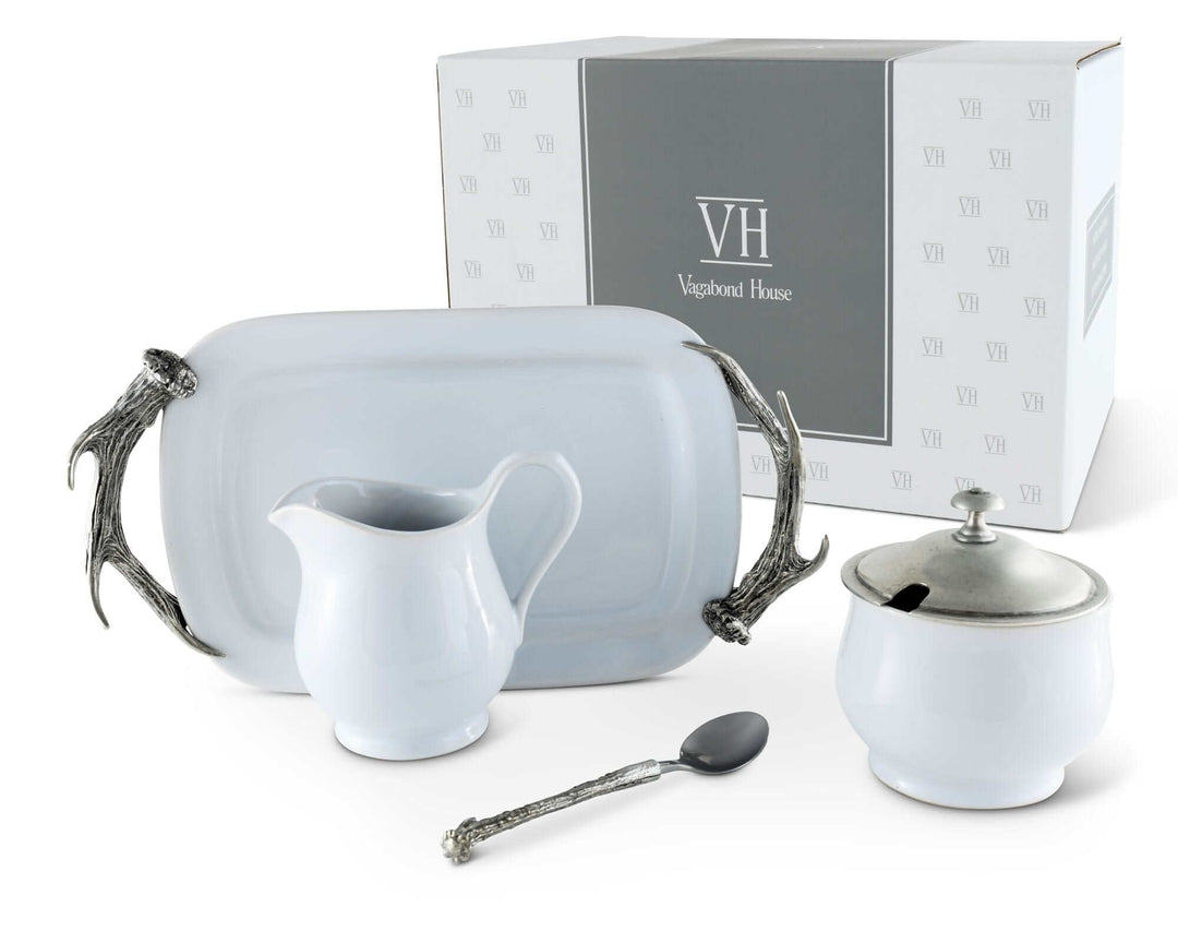 Tea set with cream pitcher, sugar bowl, and spoon in front of a branded box on a white background