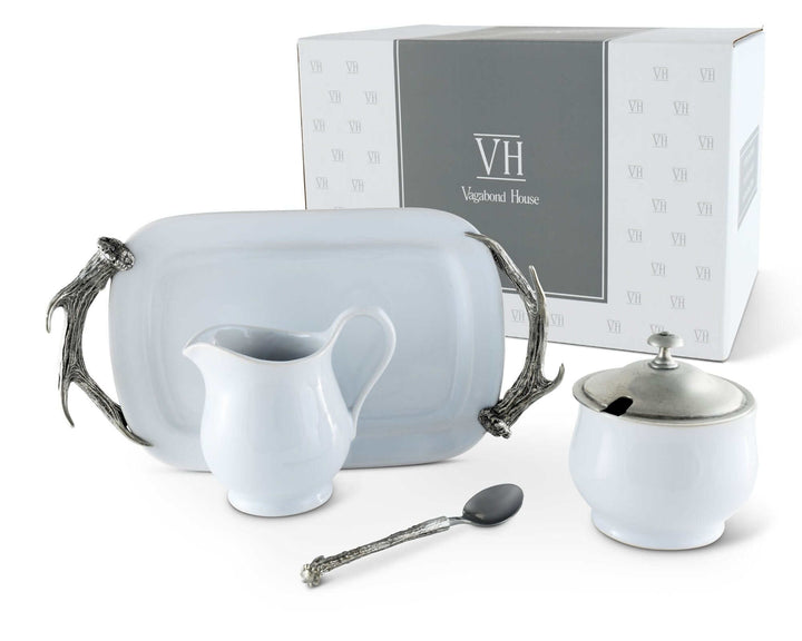 Tea set with cream pitcher, sugar bowl, and spoon in front of a branded box on a white background
