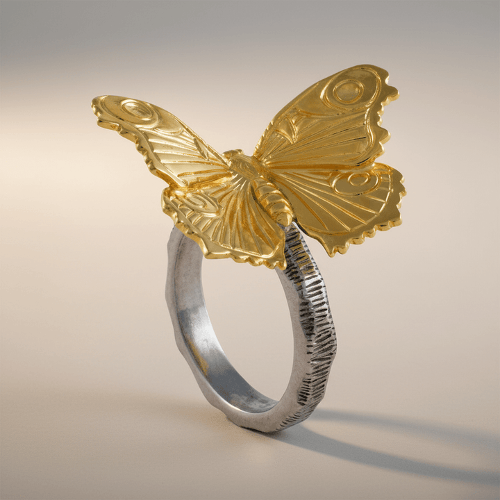 Gold butterfly napkin ring on a silver band against a gradient background