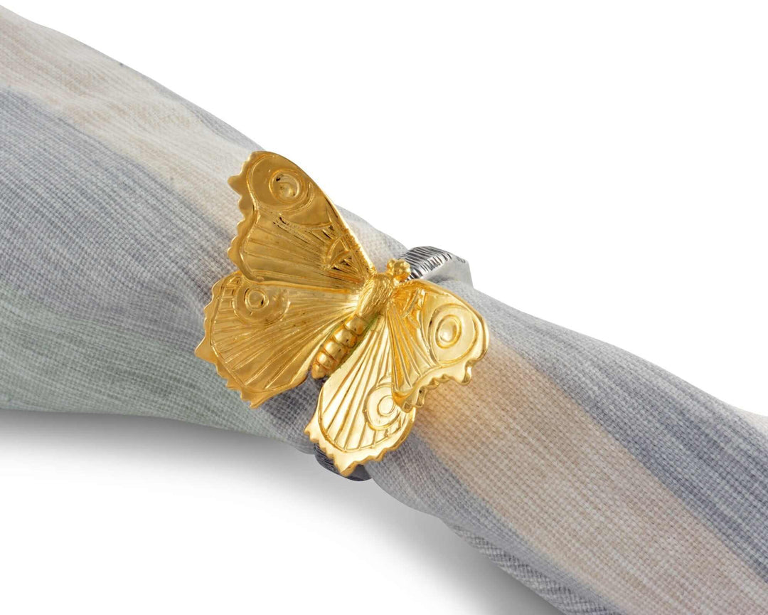 Gold butterfly-shaped napkin ring on a gray fabric background
