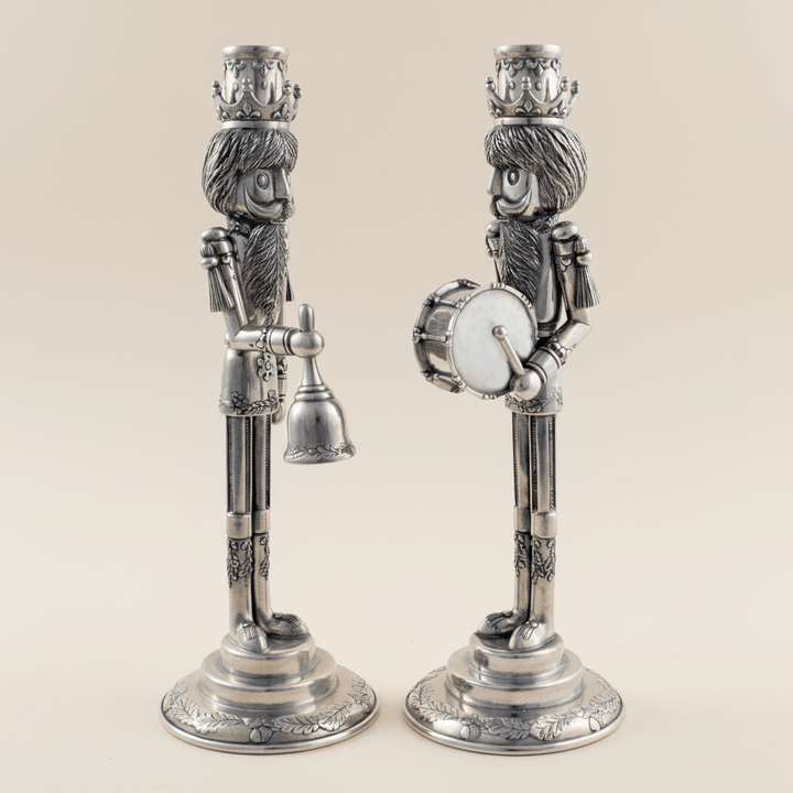Two decorative candle holders shaped like holiday nutcrackers on a beige background