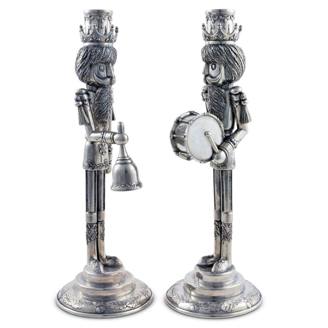Two decorative candle holders shaped like Christmas nutcrackers on a white background