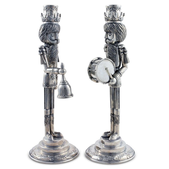 Two decorative candle holders shaped like Christmas nutcrackers on a white background