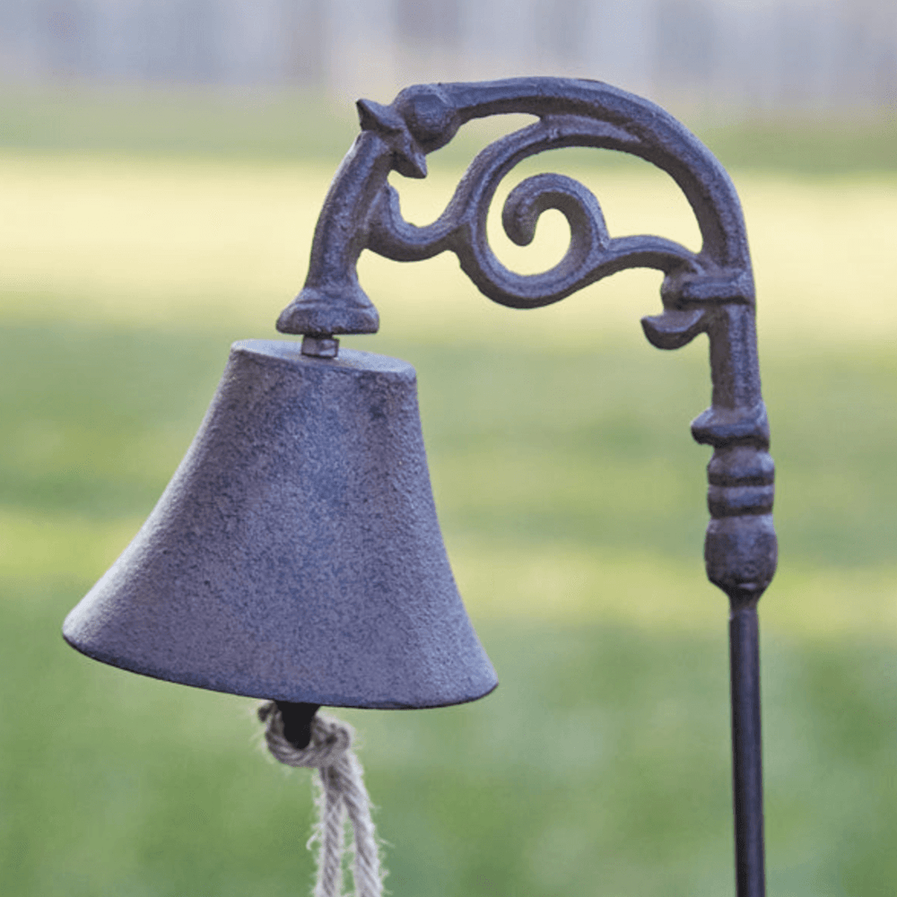 Vintage cast iron garden bell on a decorative metal stake, adding charm to outdoor spaces.