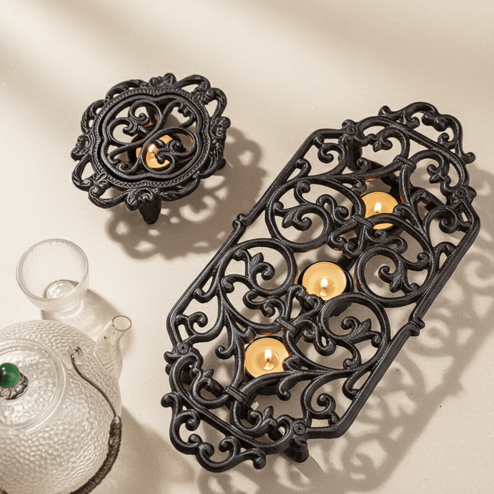 Decorative black metal teapot warmers with candles on a beige background