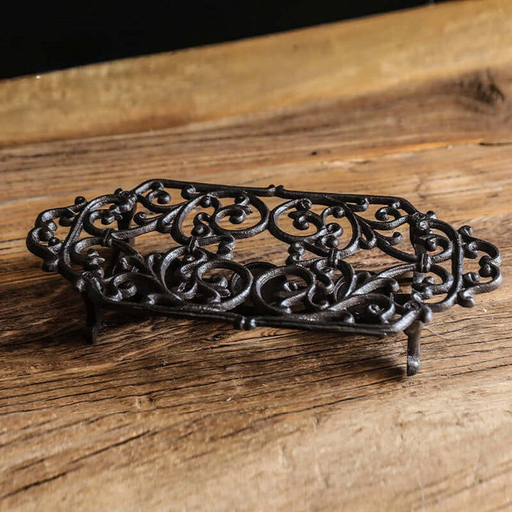 Decorative black metal trivet on a wooden surface
