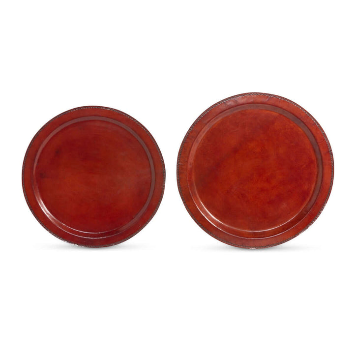 Two round red leather trays on a white background