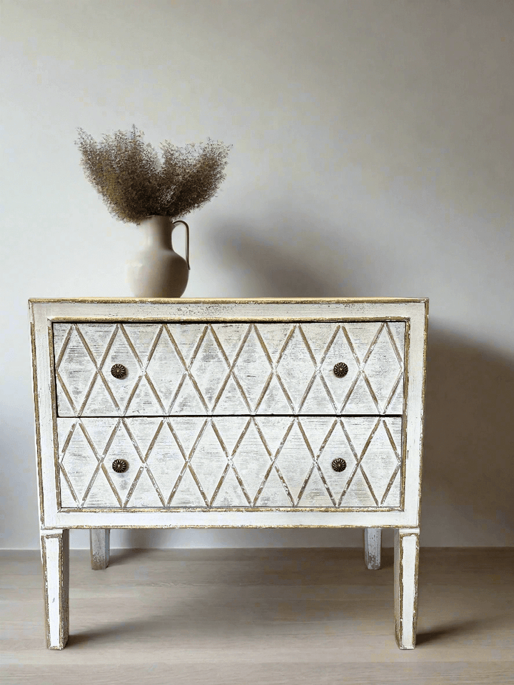 Vintage dresser with diamond pattern and vase of dried flowers, showcasing rustic charm and elegant design.