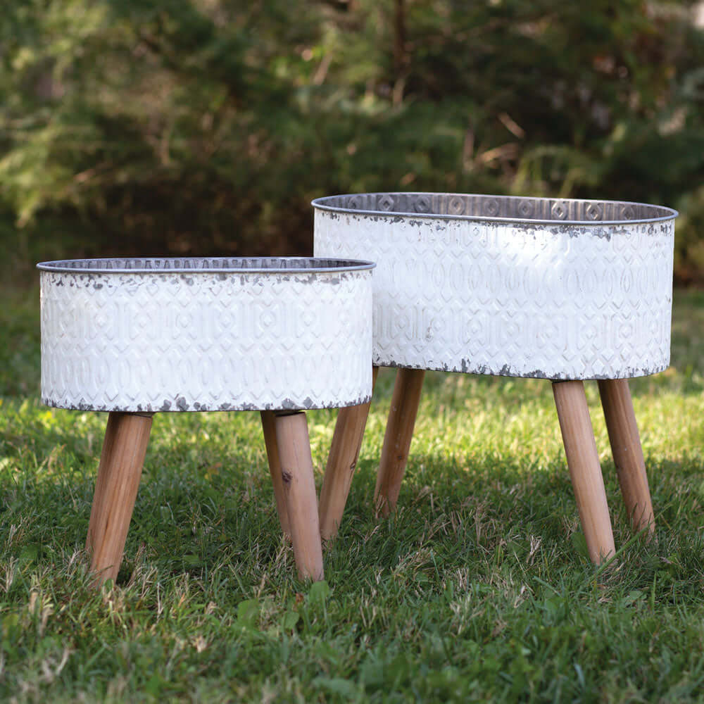 Set of 2 vintage embossed metal planters with wood legs, featuring a rustic whitewashed finish and mid-century design.
