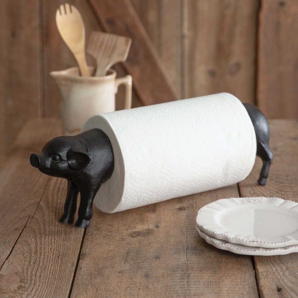 Vintage farmhouse pig paper towel holder in rustic kitchen setting with wood background.