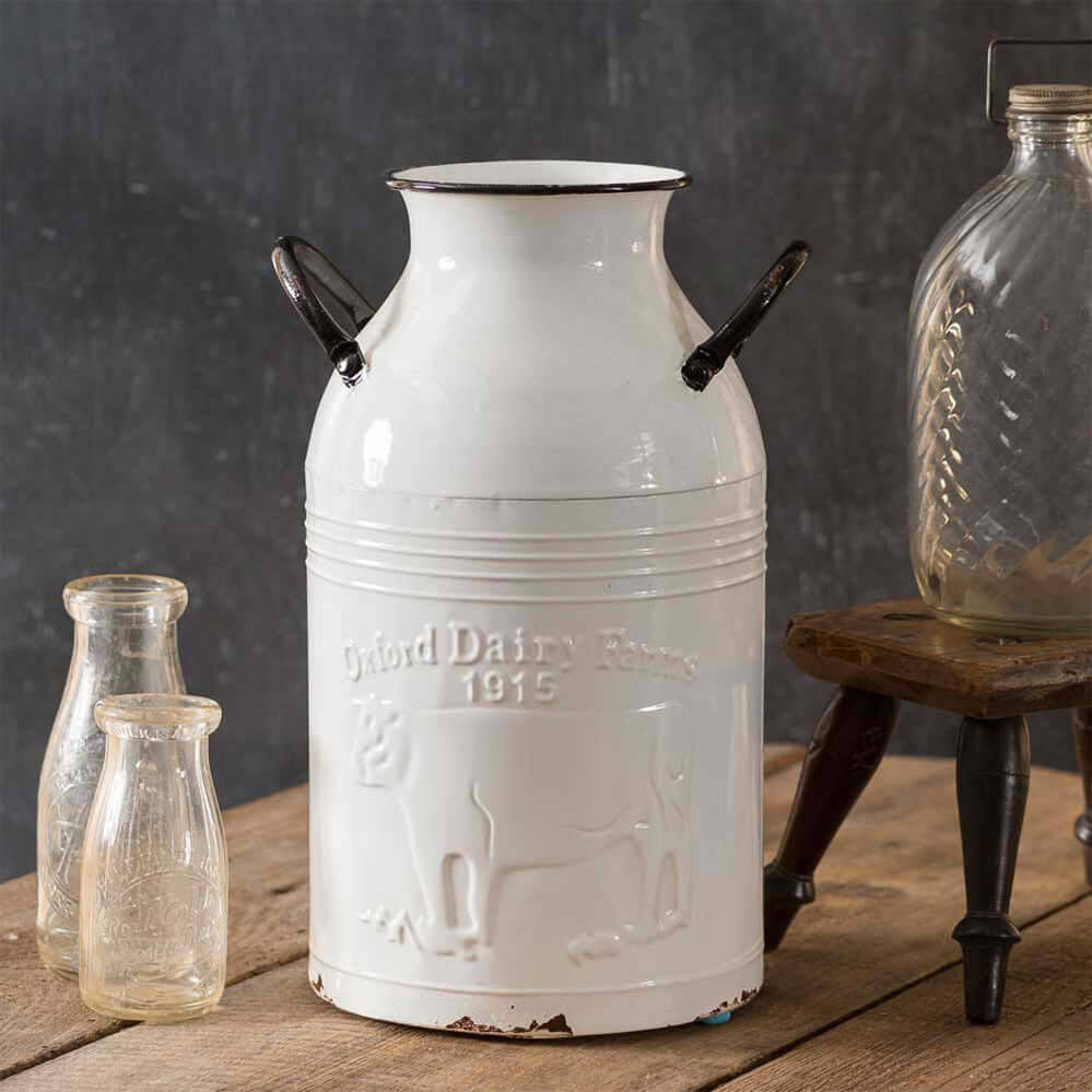 Vintage farmhouse white enamel milk can embossed with Oxford Dairy Farm 1915 and cow motif, rustic home décor.