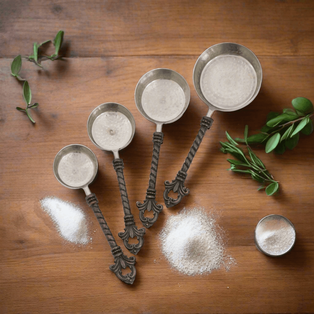 Set of decorative metal measuring cups with salt on a wooden surface
