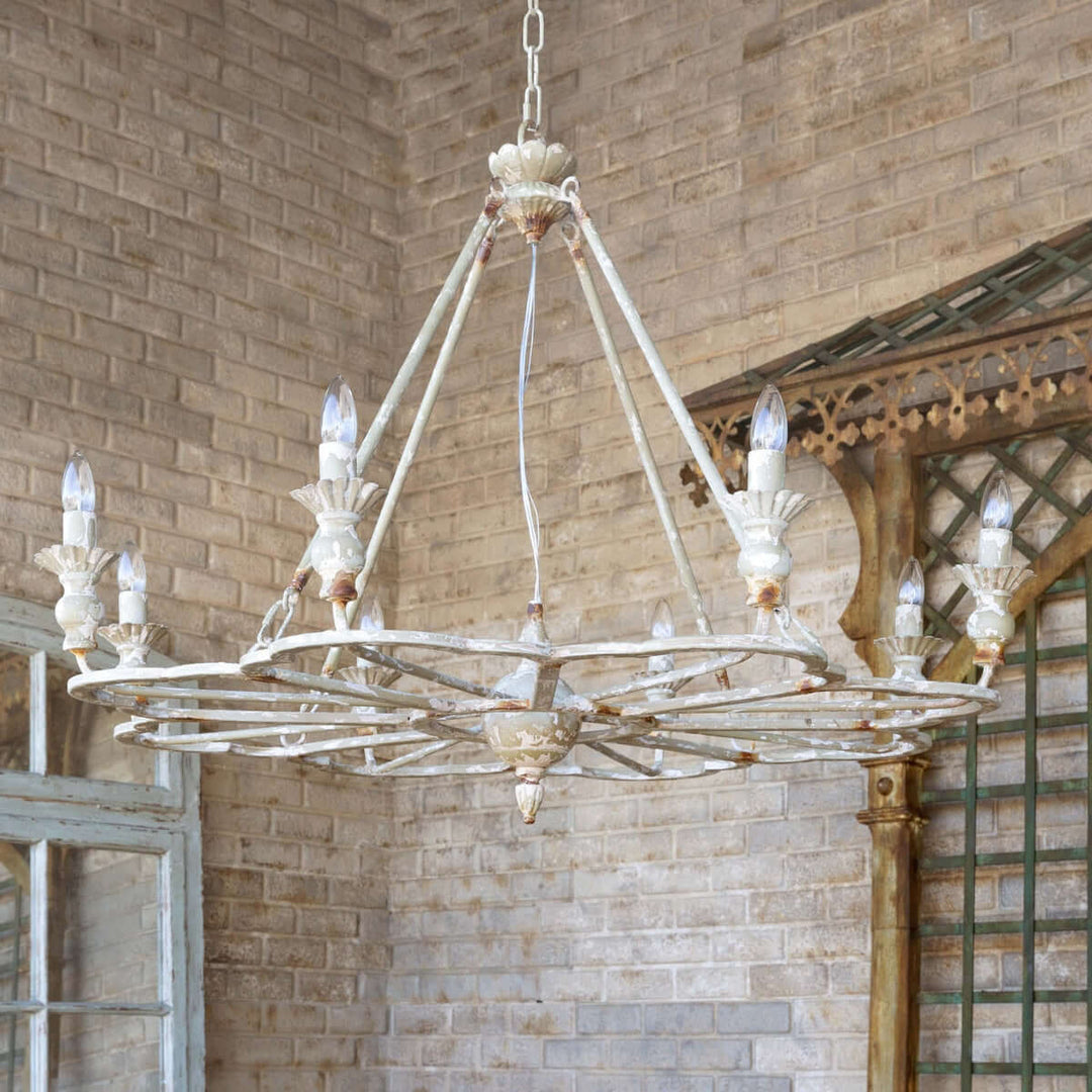 Vintage-style chandelier hanging in a room with brick walls and wooden beams.