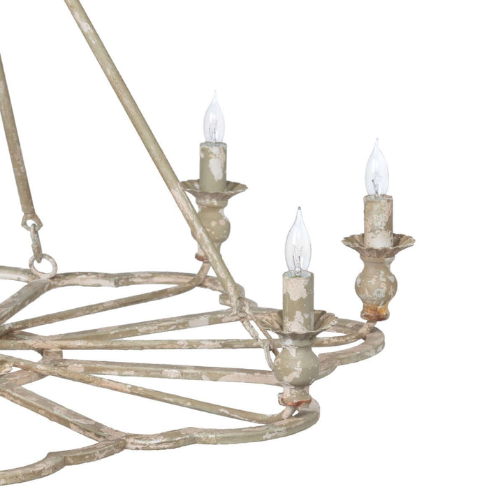 Worn metal chandelier with three lit candles on a white background