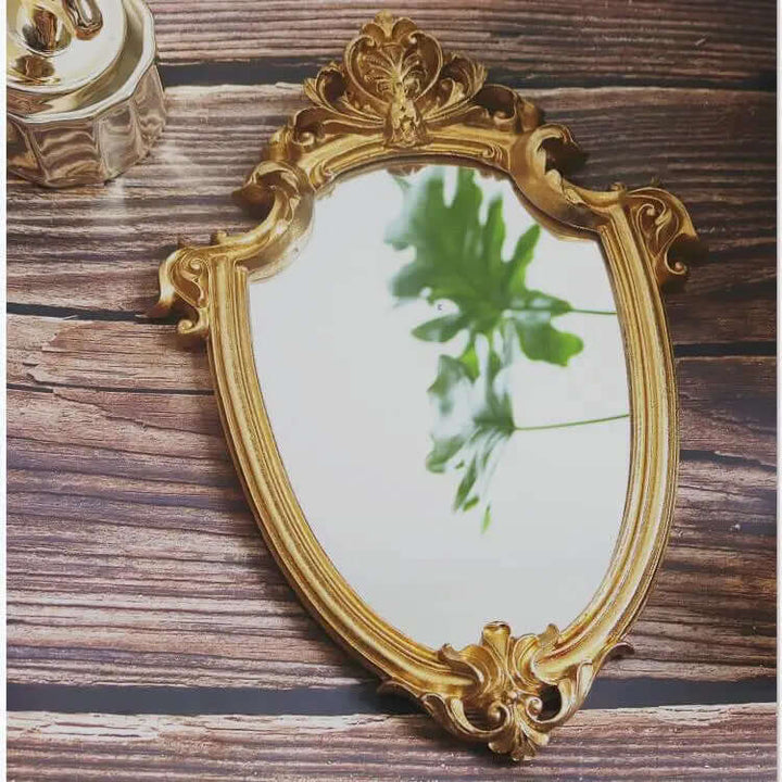 Vintage gold vanity wall mirror with Baroque frame reflecting greenery, adding elegance to your space.