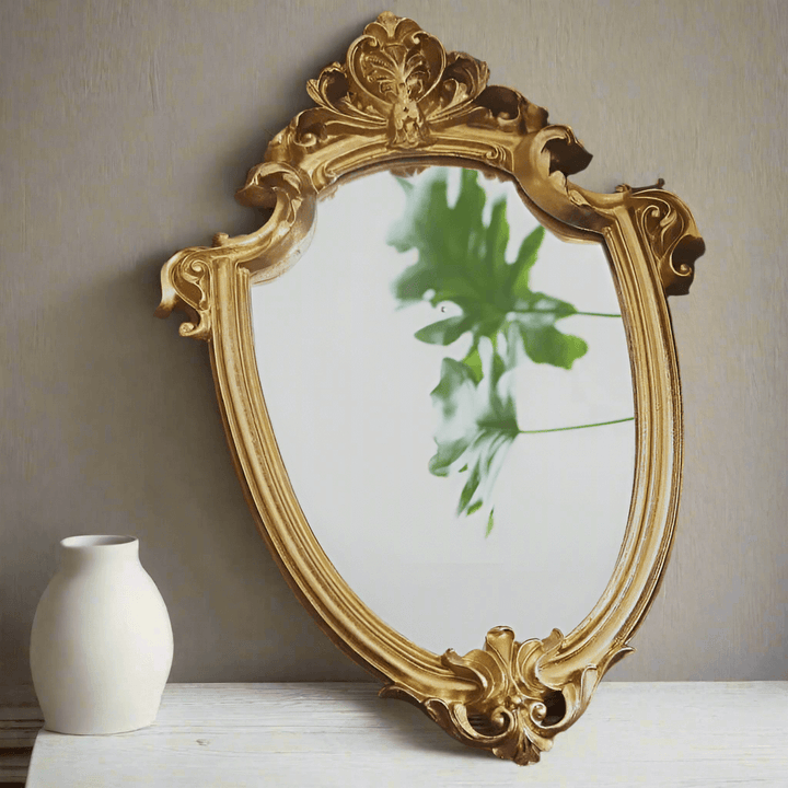 Vintage gold vanity wall mirror with Baroque frame reflecting greenery, enhancing elegant home decor.