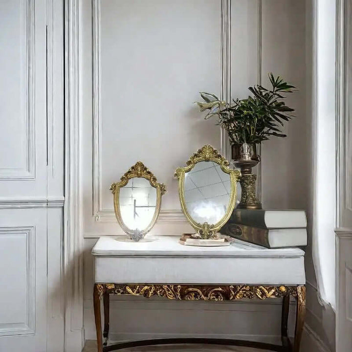 Elegant vintage gold vanity wall mirrors with Baroque frames displayed on a stylish table with decorative plant.