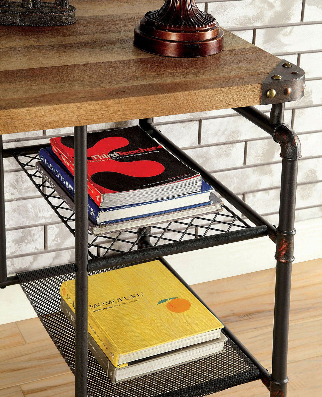Wooden desk with metal pipe legs holding books on a wooden floor.