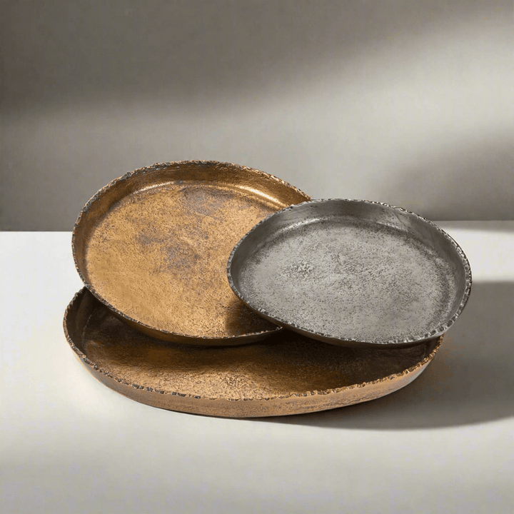 Three metal trays in gold, silver, and bronze on a light gray background