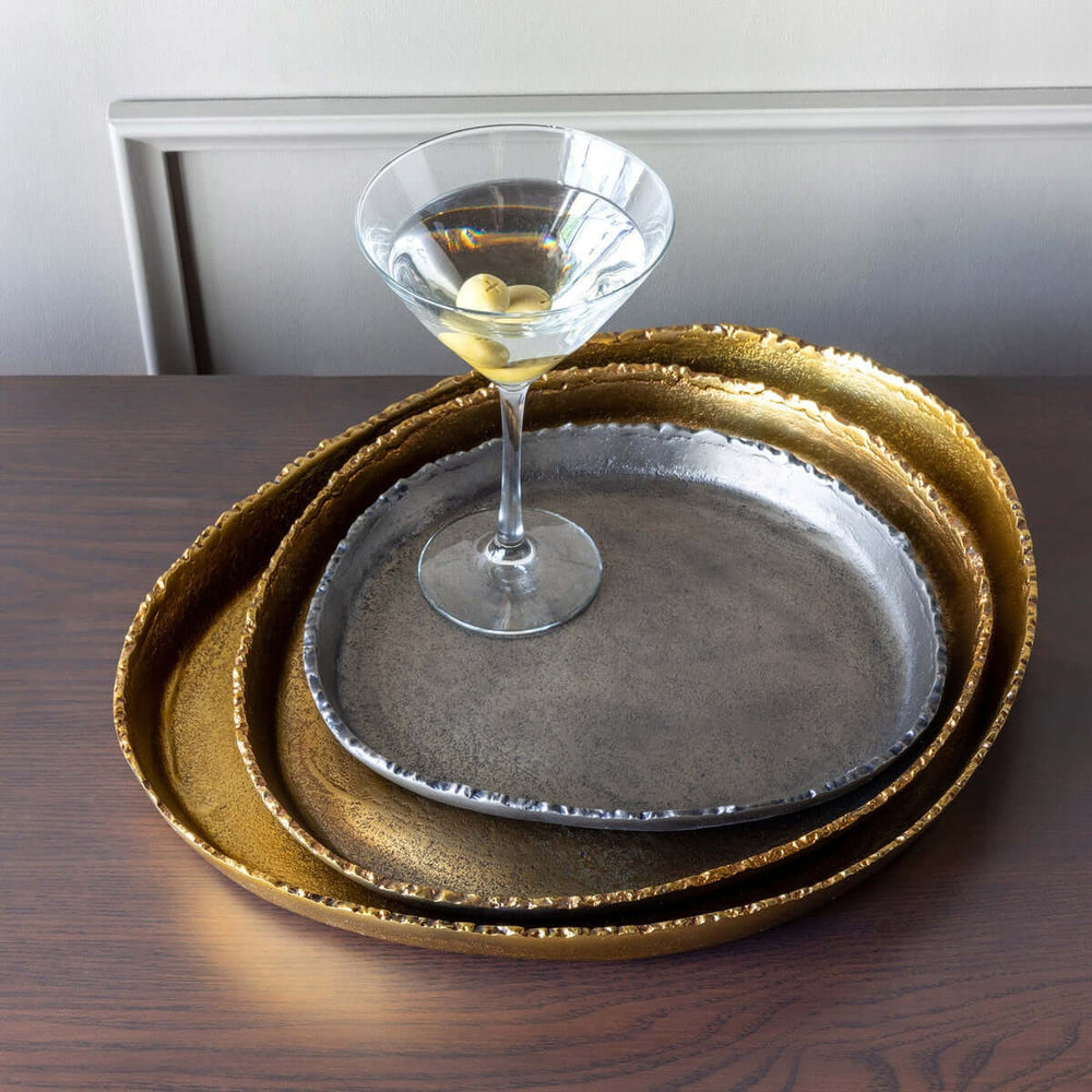 Set of gold and silver trays with a martini glass on a wooden surface