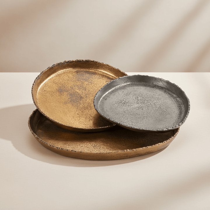 Three metallic plates in gold, bronze, and black on a beige background