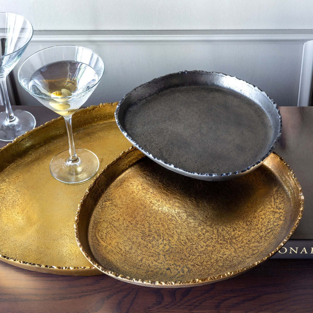 Gold and silver platters with a glass on a wooden surface