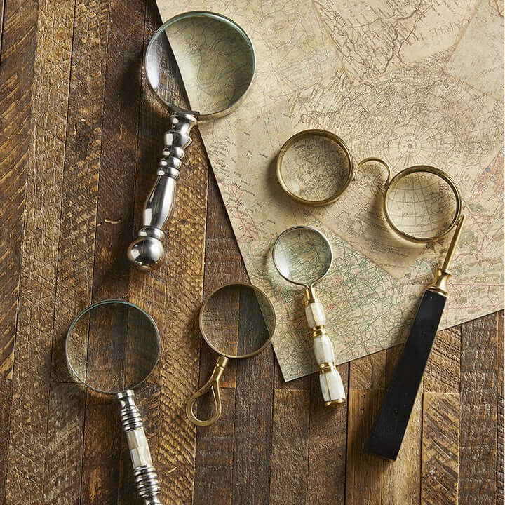 Collection of vintage-style magnifying glasses on a wooden surface with a map in the background.