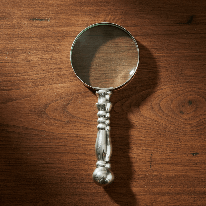 Silver magnifying glass on a wooden surface
