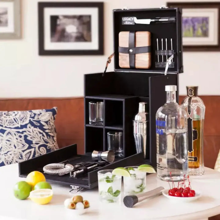 Bartender kit with bottles, glasses, and mixers on a table with a blurred background