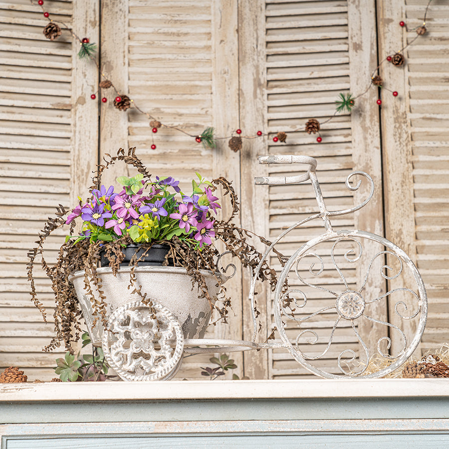 Decorative white tricycle with a flower pot on a wooden background