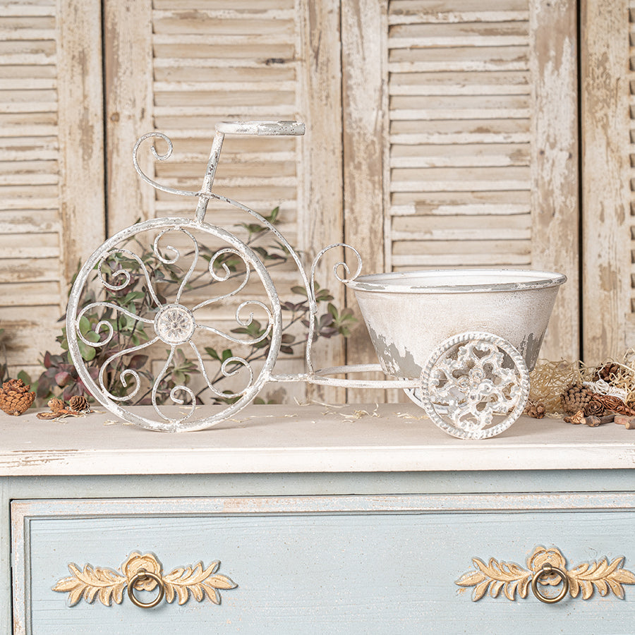 Decorative metal tricycle planter on a wooden surface with a rustic background
