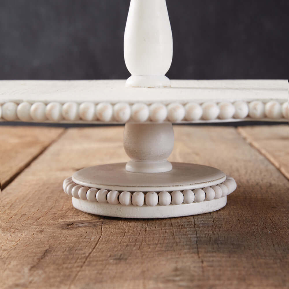 Vintage white tiered wooden tray with scalloped edges and bead-like detailing, showcasing rustic farmhouse charm.