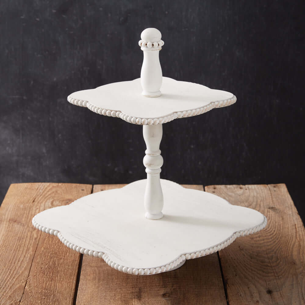 Vintage white two-tiered wooden tray with scalloped edges and bead detailing on a rustic wooden surface.