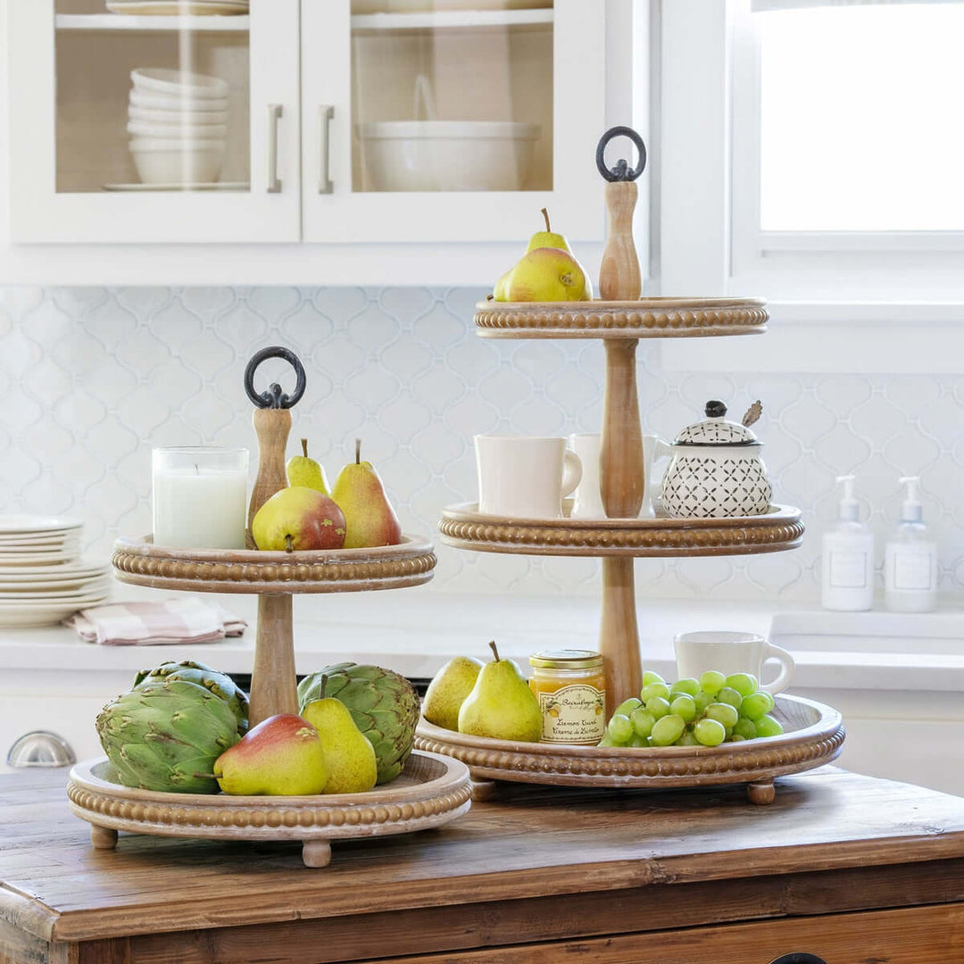 Three-tiered wooden serving tray with fruits and kitchen items on a kitchen counter.