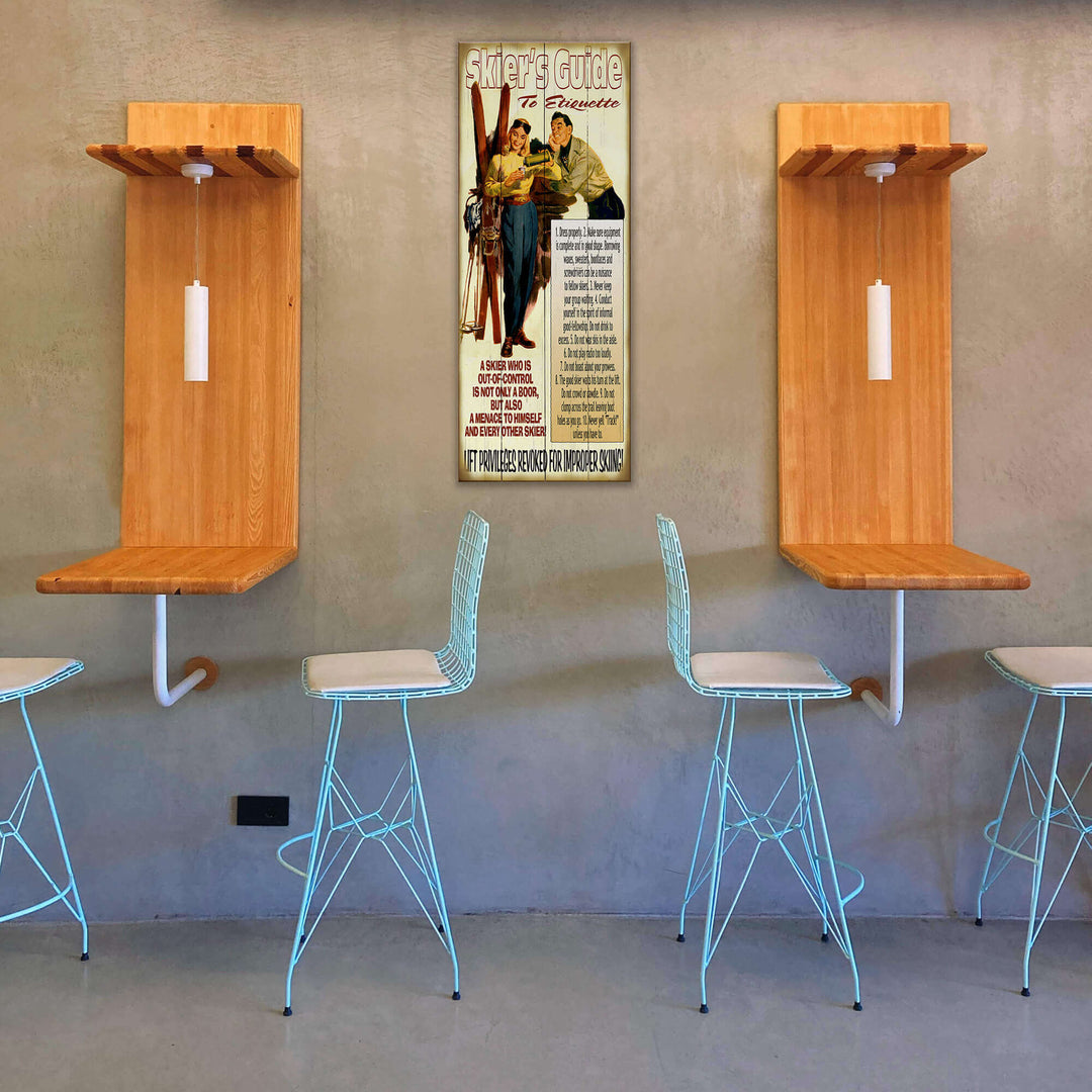 Wooden wall-mounted shelves with stools in a room with a vintage-style poster on the wall.
