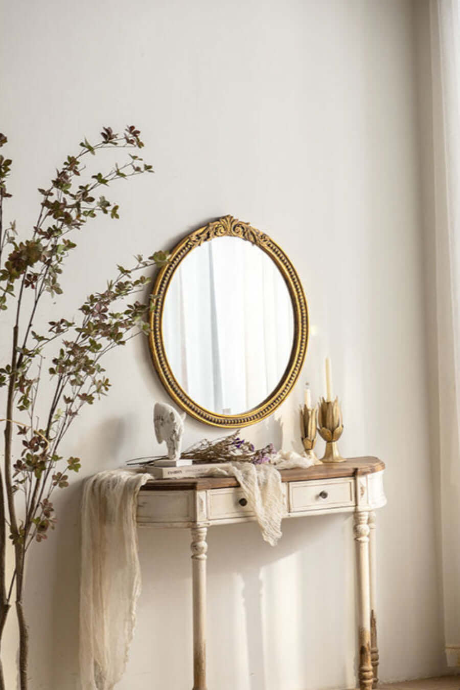 Vintage round gold mirror with ornate carved frame on antique table, elegant classic decor.