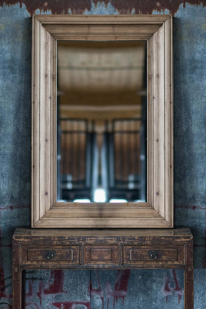 Wall mirror with molded pine frame above a vintage wooden console, reflecting a timeless and classic interior style.